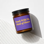 Amber jar candle with purple label reading "Stuck With Me, Maid of Honor."