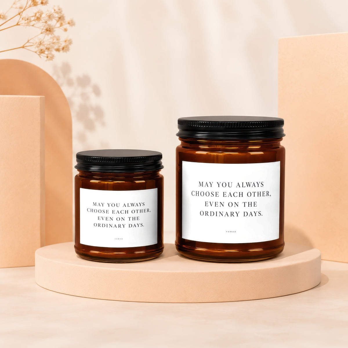 Two amber glass candles with black lids, white labels reading "May you always choose each other, even on the ordinary days."