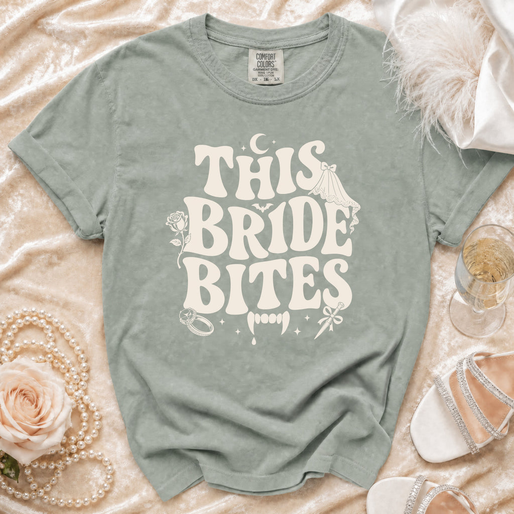 Sage t-shirt with "THIS BRIDE BITES" graphic featuring vampire teeth and wedding elements.