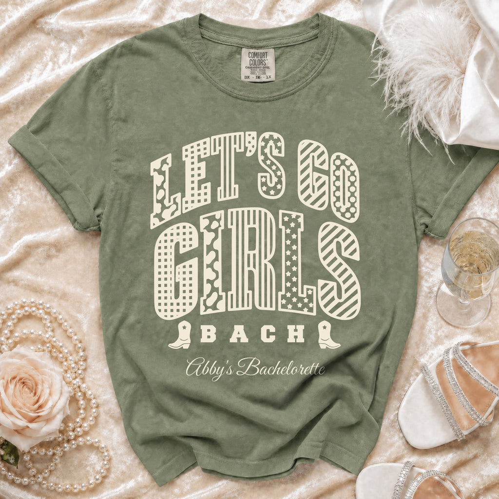 Sage green t-shirt with Let's Go Girls Bach and Abby's Bachelorette text printed in cream.