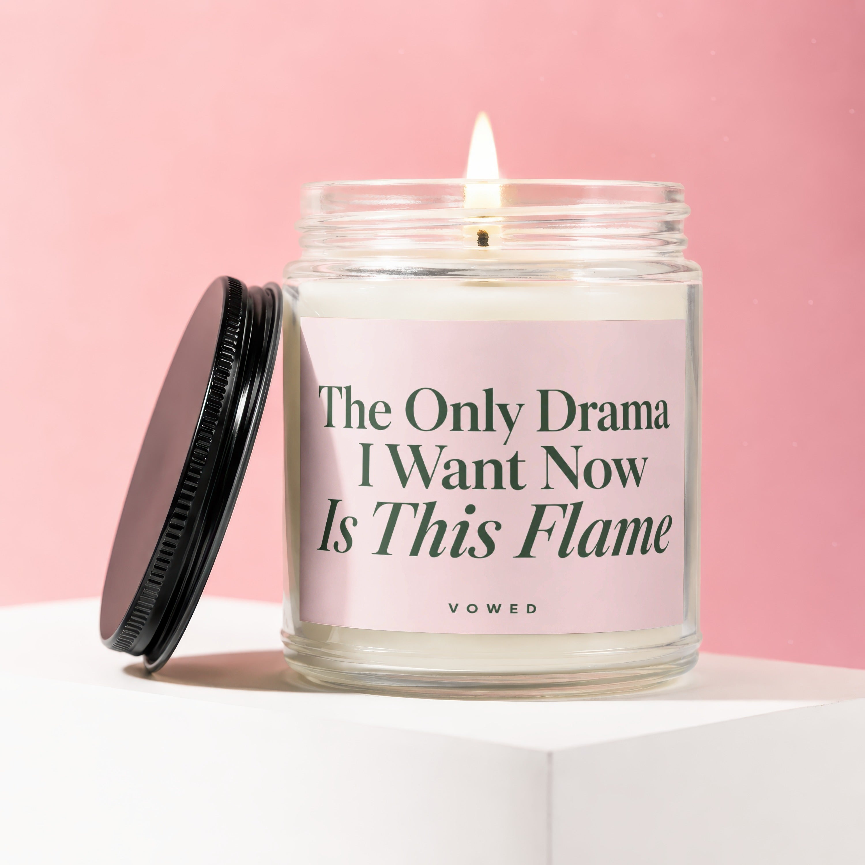 Glass candle with lit flame and pink label reading "The Only Drama I Want Now Is This Flame"