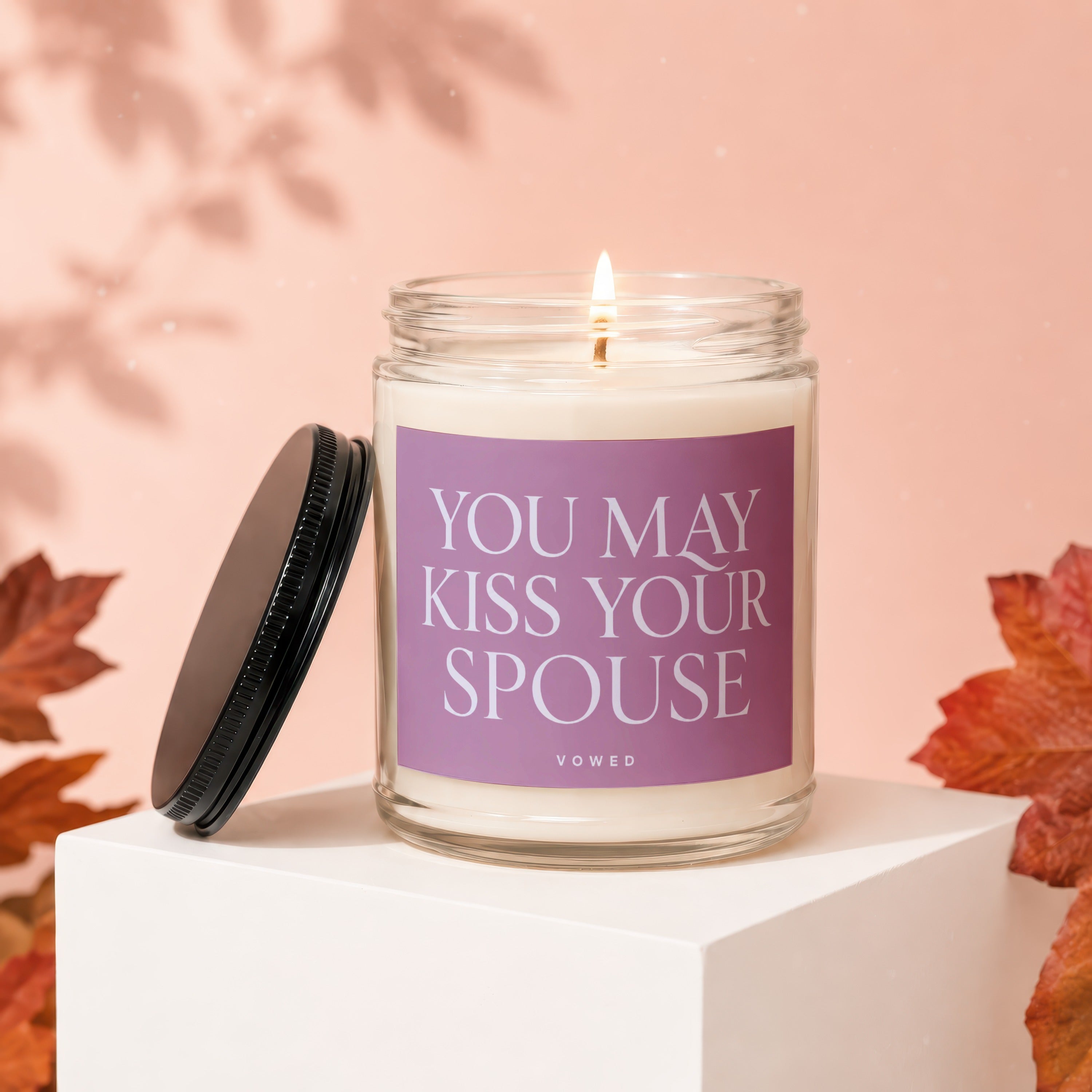 Lit candle in glass jar with "YOU MAY KISS YOUR SPOUSE" text on label.