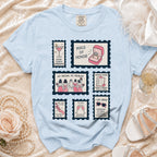 Light blue t-shirt with "Maid of Honor" themes in stamp graphics.