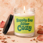 Candle with green label reading "Happily Ever After Cozy" on a peach background.