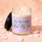 Lit candle in a jar with a pink label that reads "May This Candle Heal My Feet"