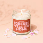 Candle with lit wick featuring text "Confirmed: Forever Feels Like Home".