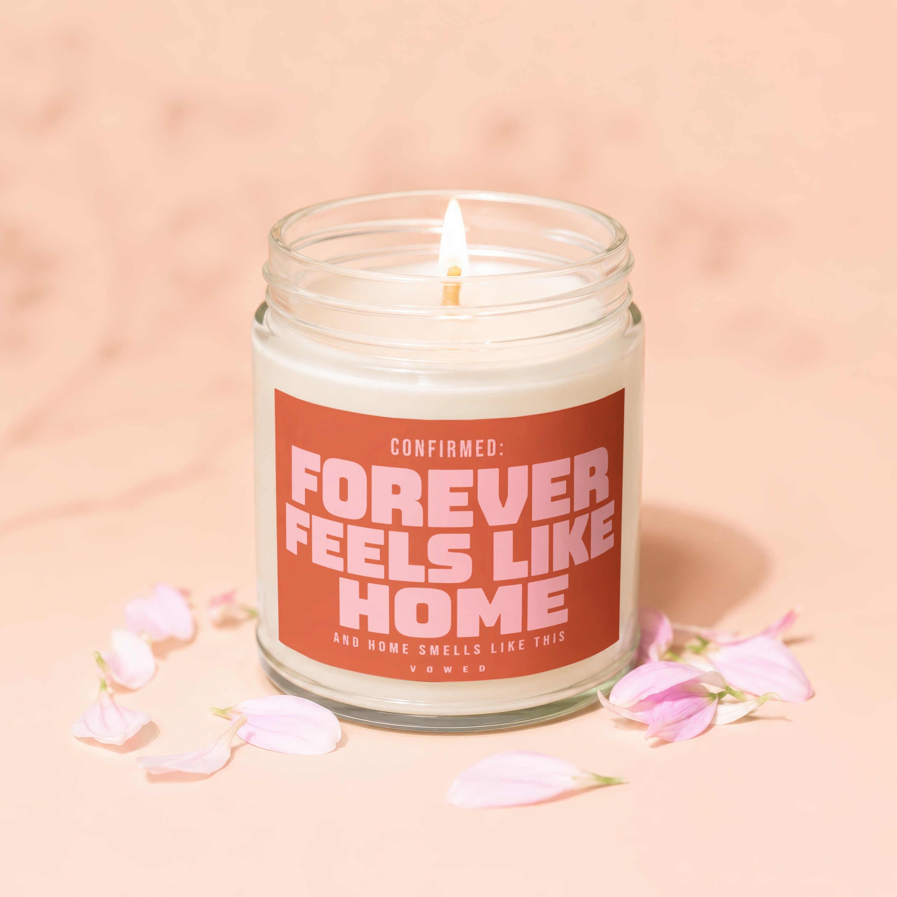 Candle with lit wick featuring text "Confirmed: Forever Feels Like Home".