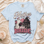 Light blue t-shirt with "Mother of the Bride" text, ghost, haunted house, and roses graphic.