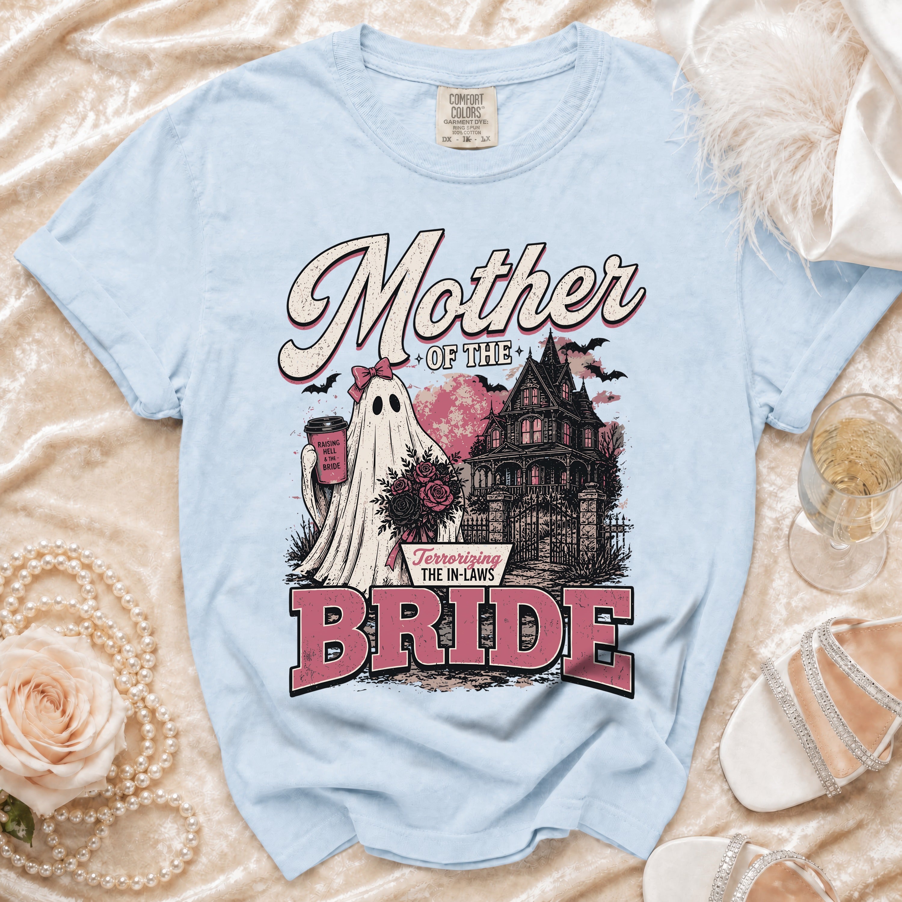 Light blue t-shirt with "Mother of the Bride" text, ghost, haunted house, and roses graphic.