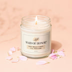 Candle with label "MAID OF HONOR? YOU WALK FIRST. I'LL FOLLOW." surrounded by petals.
