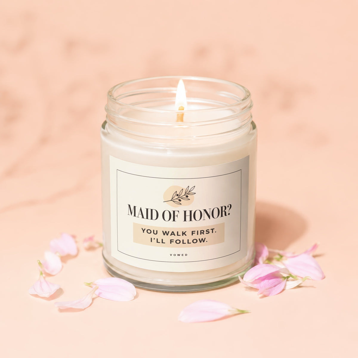 Candle with label "MAID OF HONOR? YOU WALK FIRST. I'LL FOLLOW." surrounded by petals.