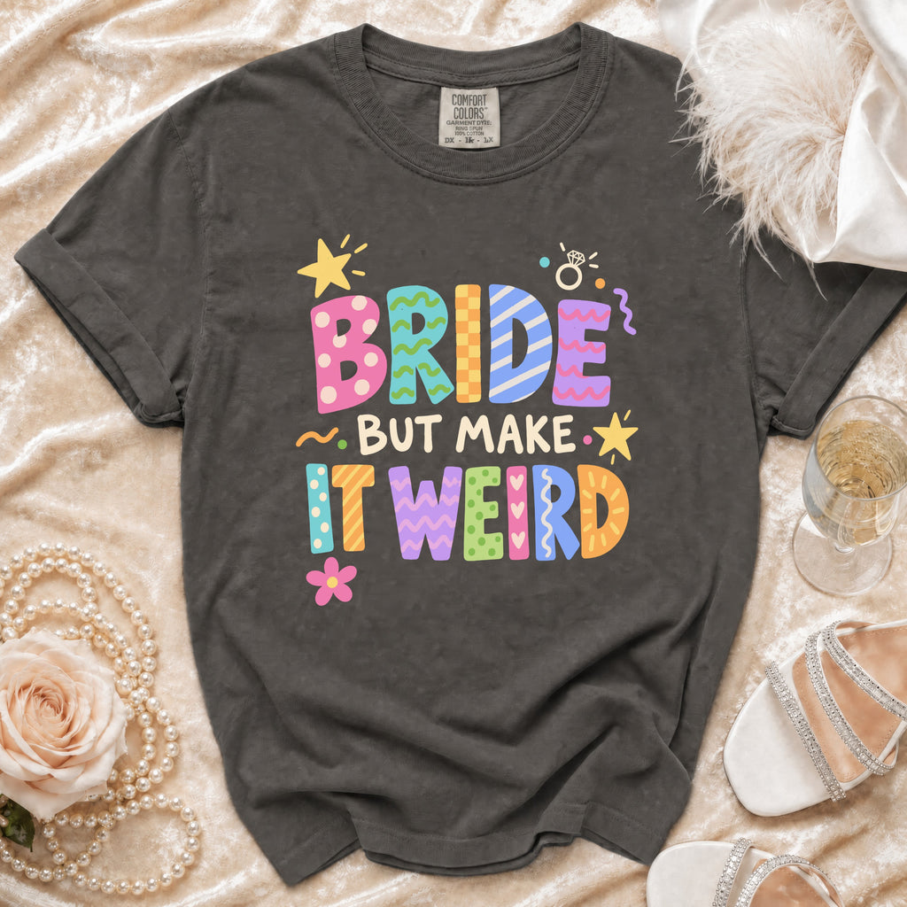 Dark gray t-shirt with "BRIDE BUT MAKE IT WEIRD" text in colorful, patterned letters.