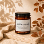 Amber jar candle with black lid, featuring "bridesmaid" definition label.