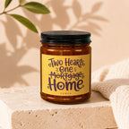 Brown glass candle with yellow label that reads "Two Hearts, One Mortgage Home".
