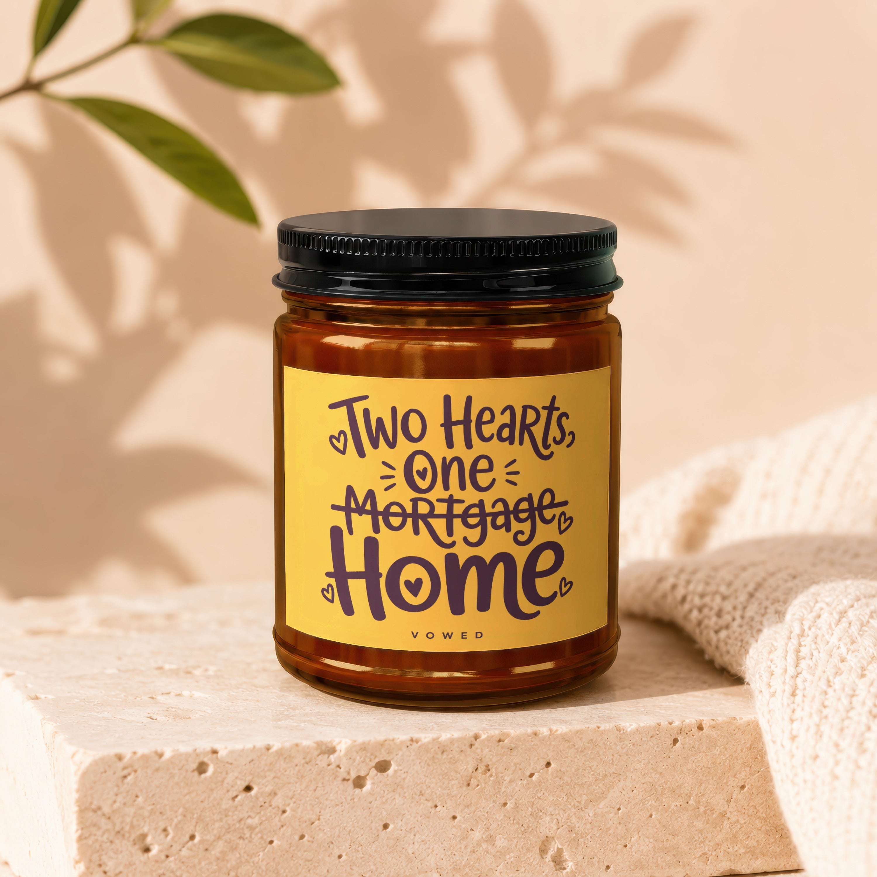 Brown glass candle with yellow label that reads "Two Hearts, One Mortgage Home".