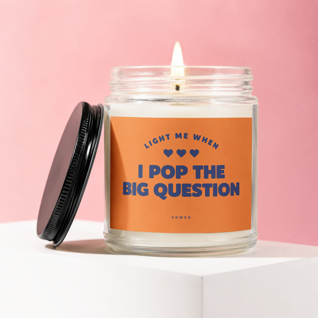 Candle with orange label reading "Light me when I pop the big question" and "vowed".