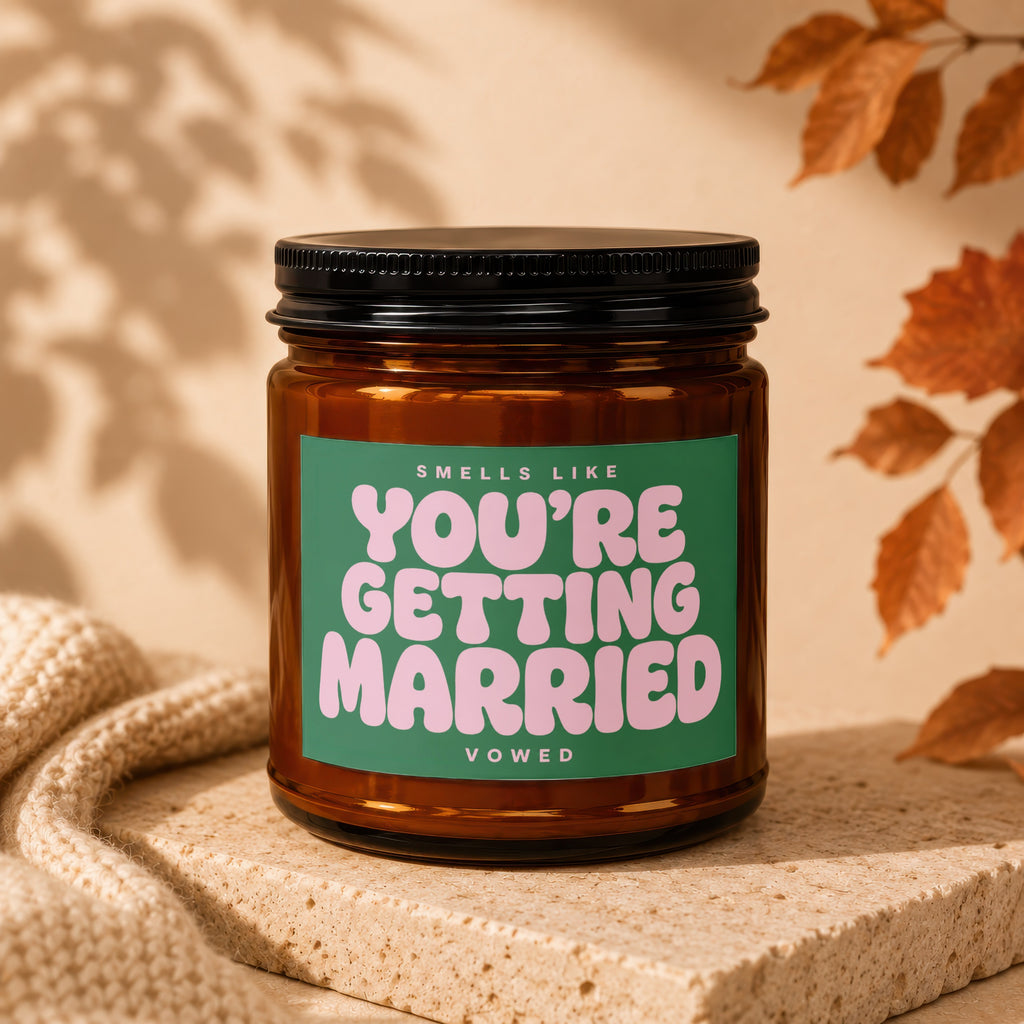 Amber candle with green label reading "Smells like You're Getting Married Vowed".