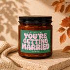 Amber candle with green label reading "Smells like You're Getting Married Vowed".