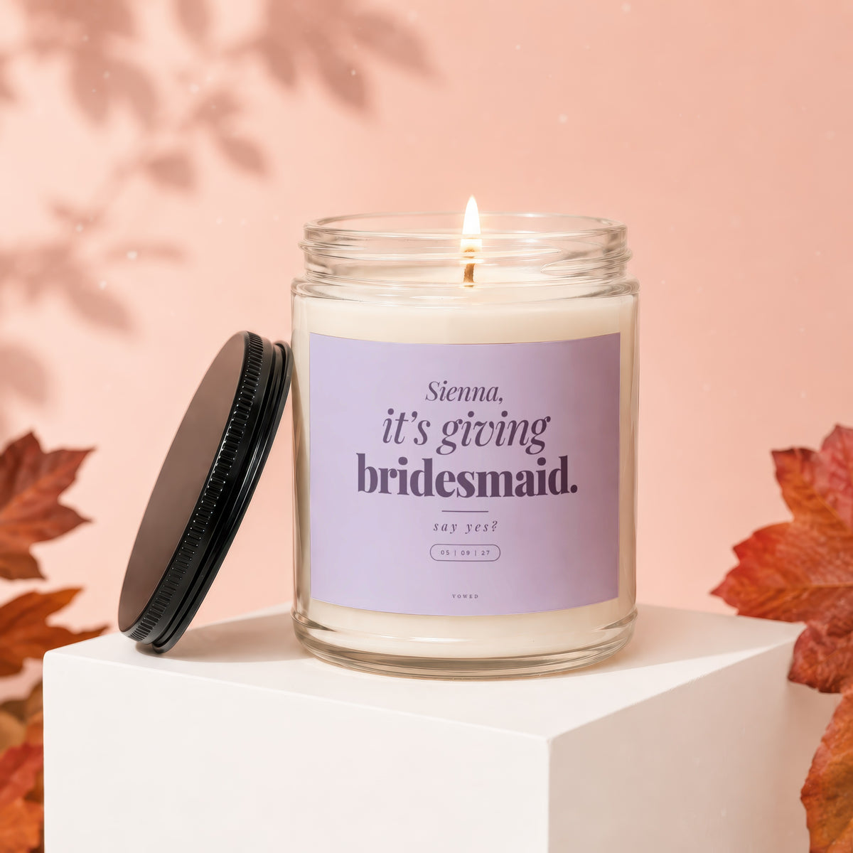 Candle with purple label reading "Sienna, it's giving bridesmaid. say yes?"