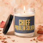 Candle with label reading "TITLE: CHIEF PROBLEM SOLVER UNPAID. UNMATCHED. UNBOTHERED. VOWED."