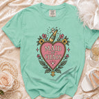 Teal t-shirt with "Maid of Chaos" text and champagne bottle graphic.