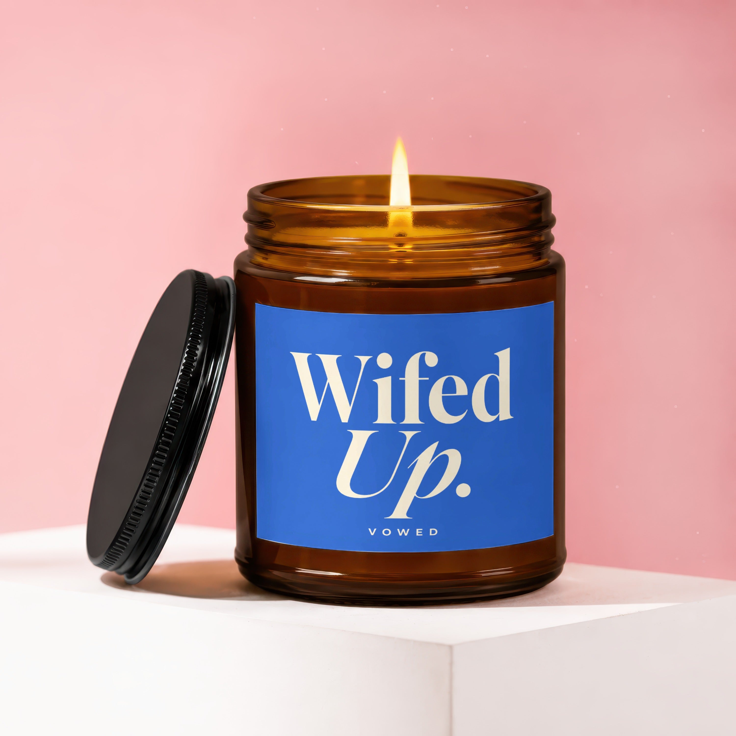 Amber glass candle with lit wick and blue label reading "Wifed Up."