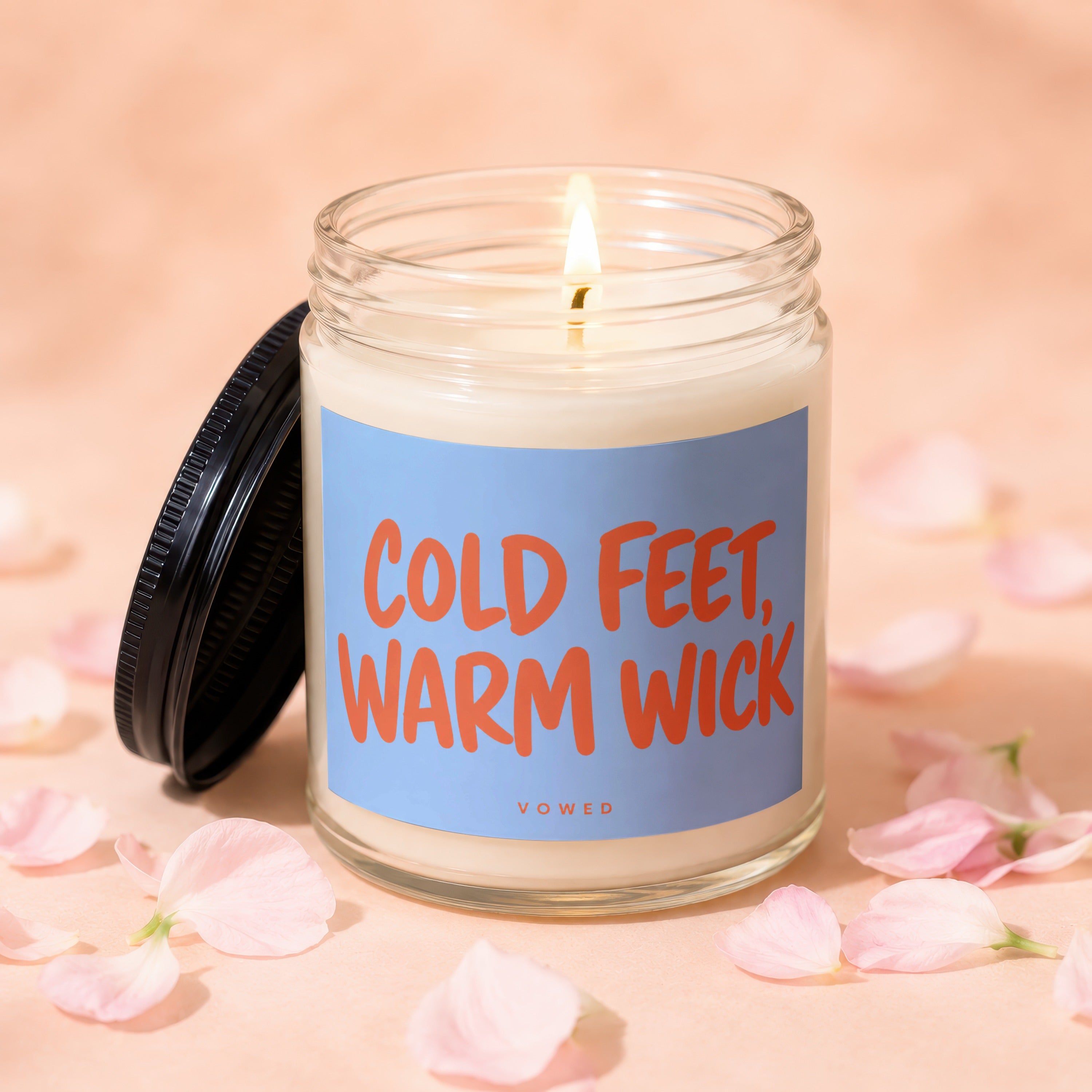 Glass jar candle with "COLD FEET, WARM WICK" on blue label, lid ajar.
