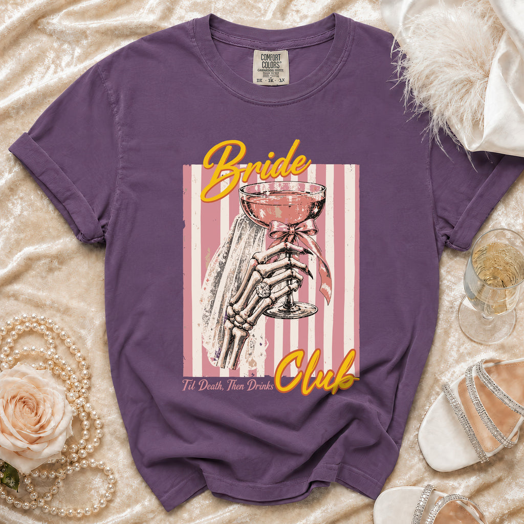 Purple t-shirt with "Bride Club" graphic featuring a skeleton hand holding a champagne glass.