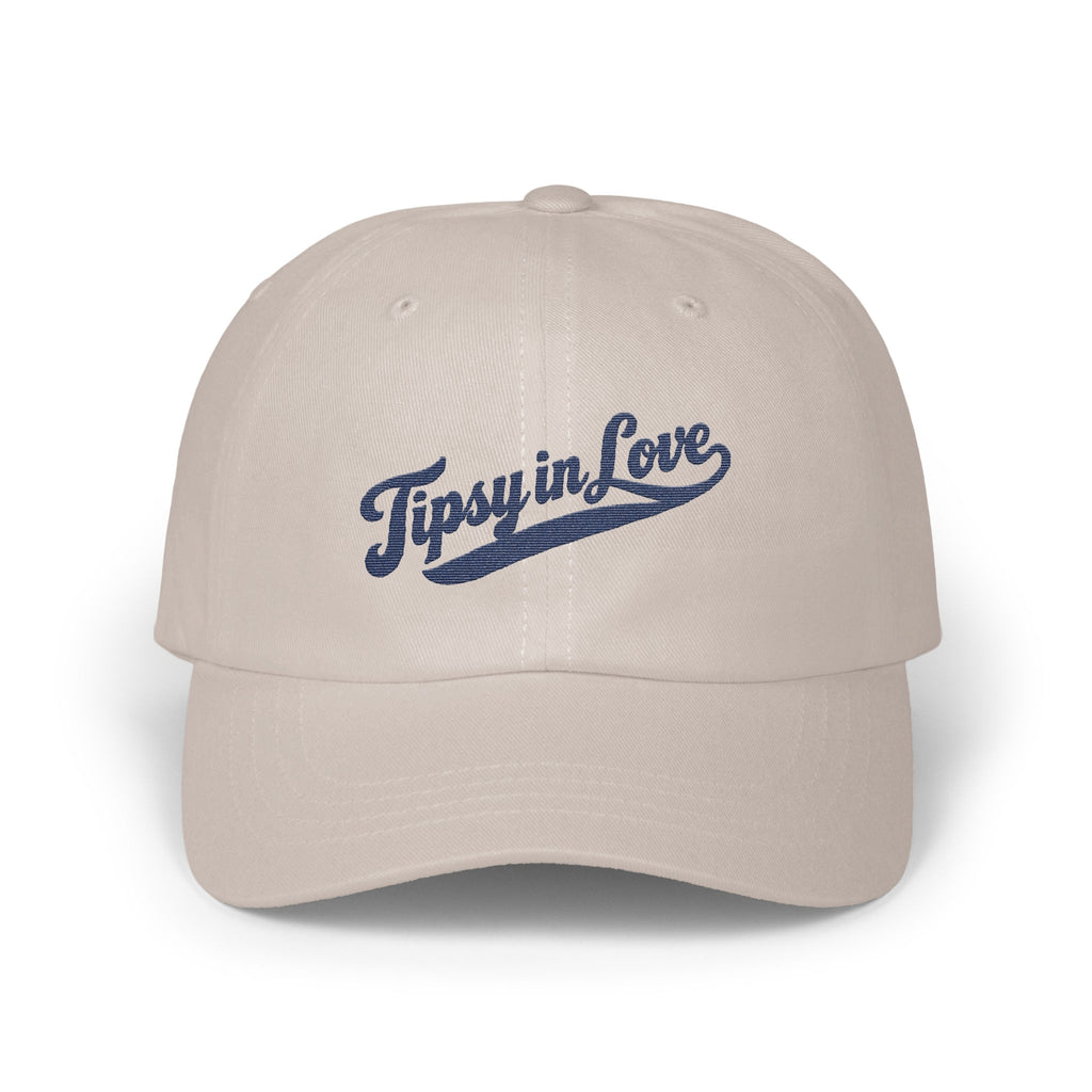 Light beige baseball cap with the blue embroidered text Tipsy in Love across the front.