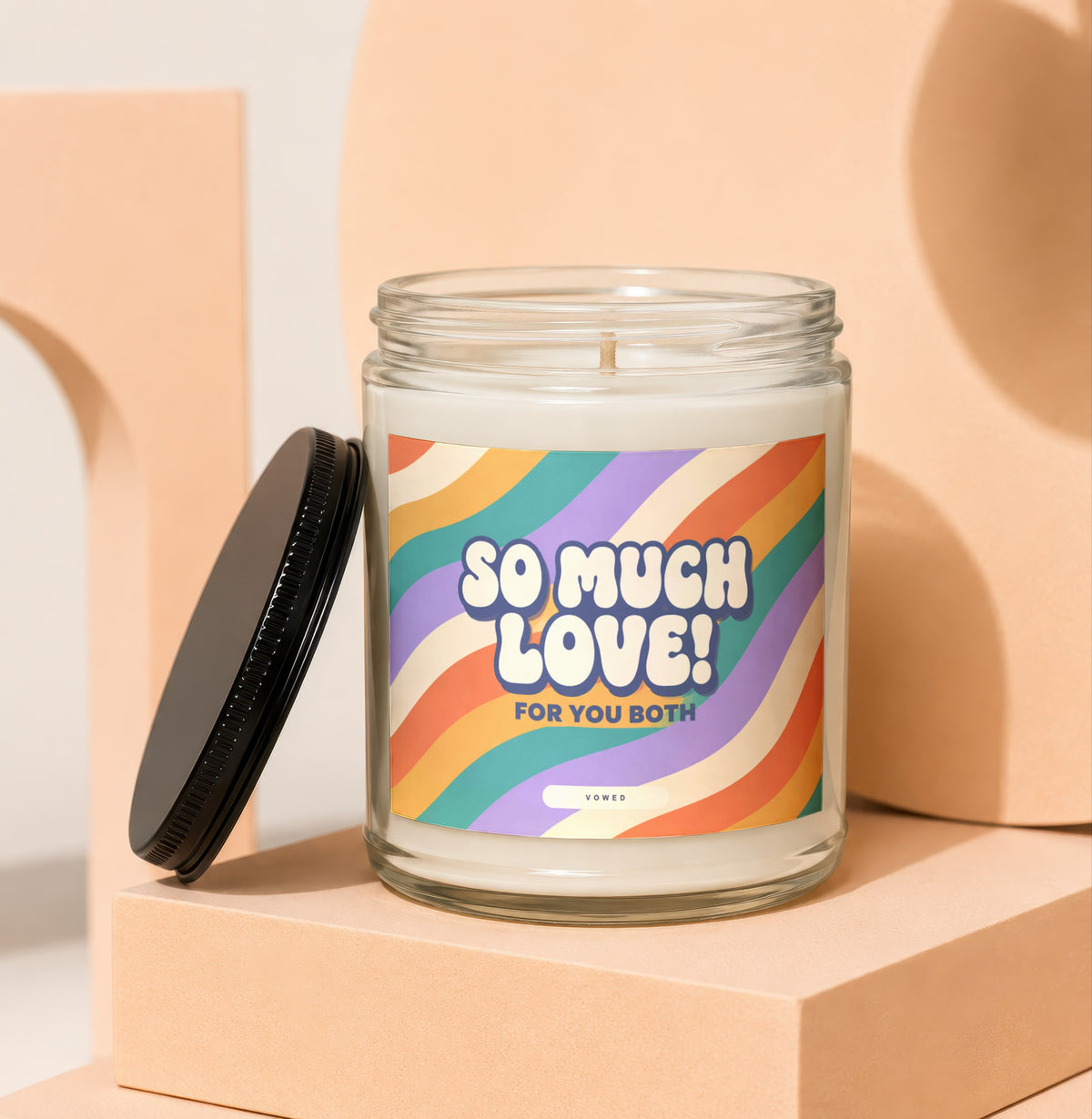 Candle with label reading "So Much Love! For You Both" on a colorful rainbow stripe background.