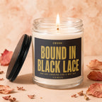 Glass candle with lit wick and label reading "SWORN: BOUND IN BLACK LACE AND NOT LOOKING FOR A WAY OUT VOWED".