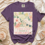 Purple t-shirt with "This girl needs a margarita" text and floral margarita graphic.