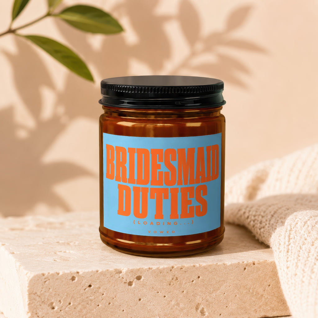 Brown jar candle with blue and orange label that reads "BRIDESMAID DUTIES (LOADING...)" and "VOWED".