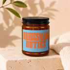 Brown jar candle with blue and orange label that reads "BRIDESMAID DUTIES (LOADING...)" and "VOWED".