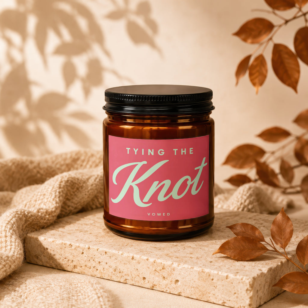 Brown glass candle with pink label reading "TYING THE Knot VOWED".