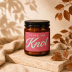 Brown glass candle with pink label reading "TYING THE Knot VOWED".