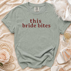 Sage green t-shirt with "this bride bites" text, styled with pearls and heels.