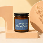 Brown glass candle with label "SURVIVED the Ritual" by VOWED.