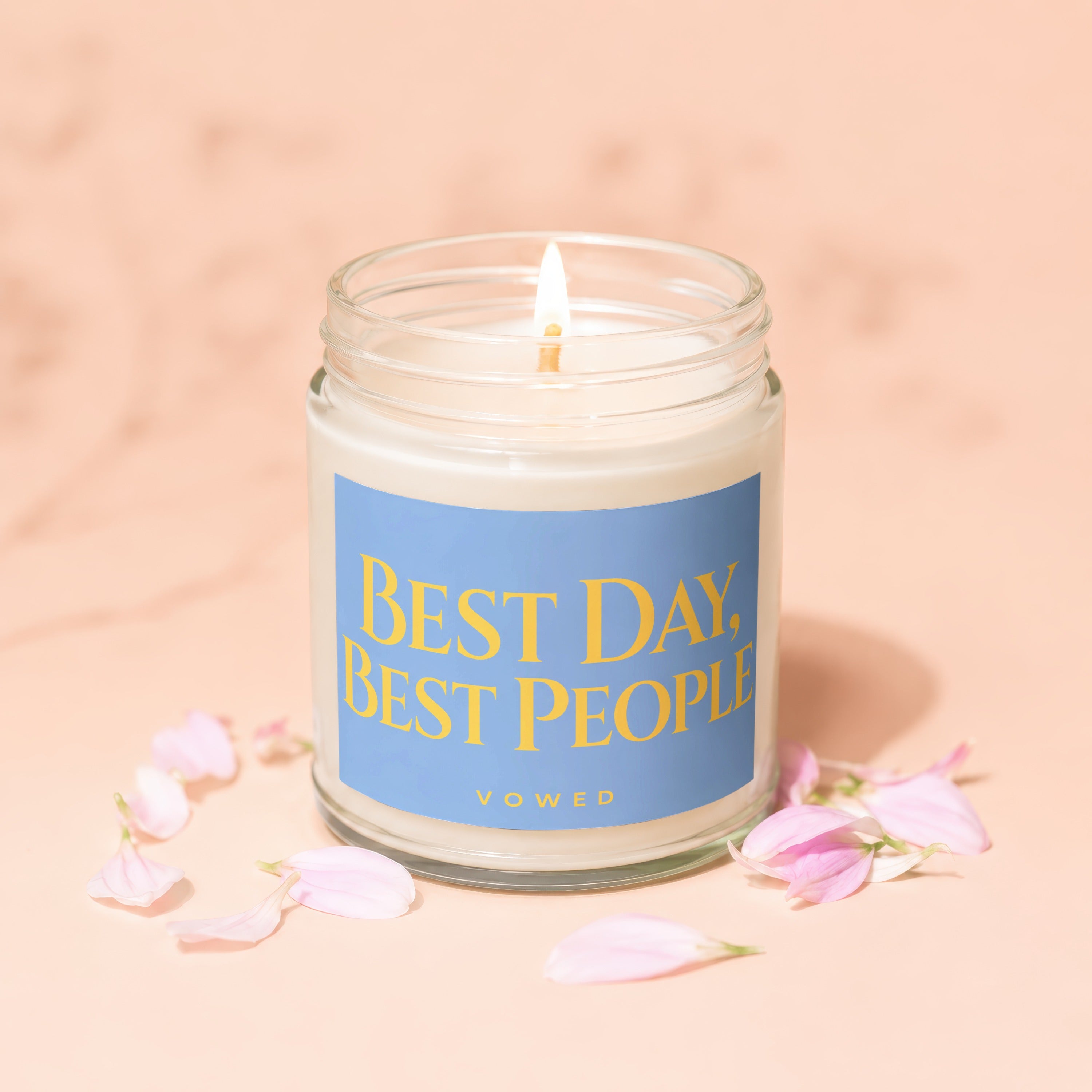 Glass jar candle with lit wick featuring a blue label with yellow text: "BEST DAY, BEST PEOPLE."