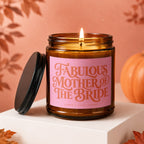 Candle with pink label reading "Fabulous Mother of the Bride," lit flame.