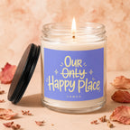 Lit candle in glass jar with purple label saying "Our Only Happy Place"