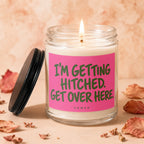 Lit candle in glass jar with pink label reading "I'M GETTING HITCHED. GET OVER HERE. VOWED."
