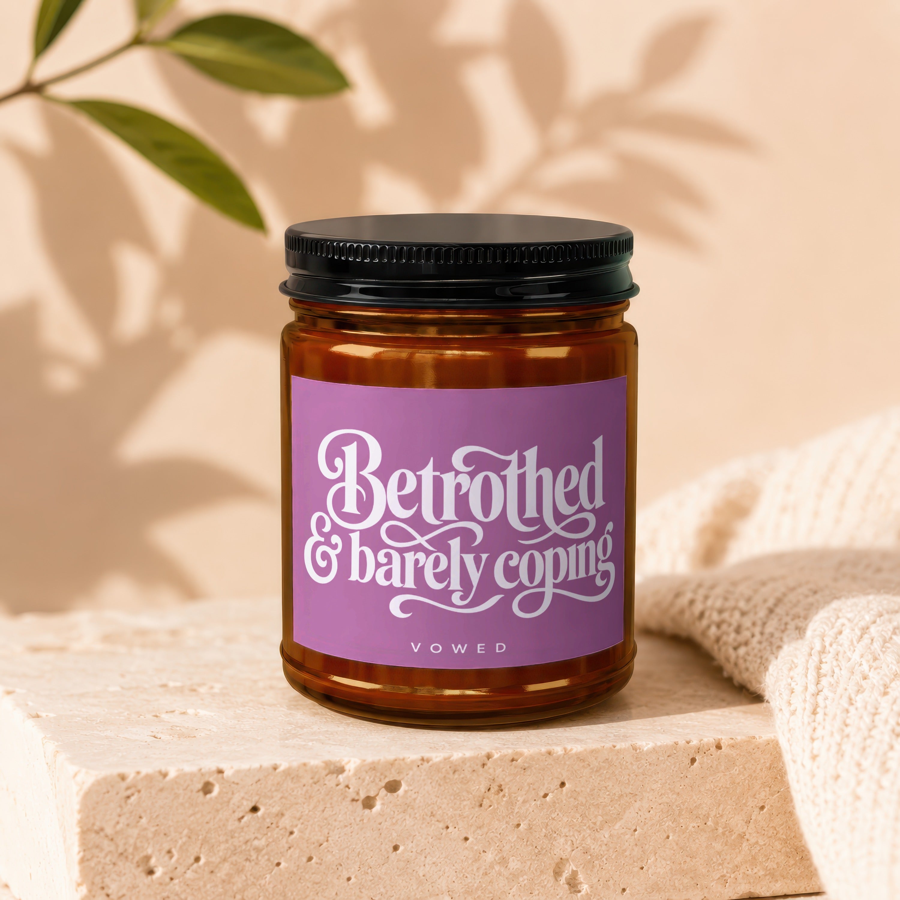Candle with purple label reading "Betrothed & barely coping" by VOWED.
