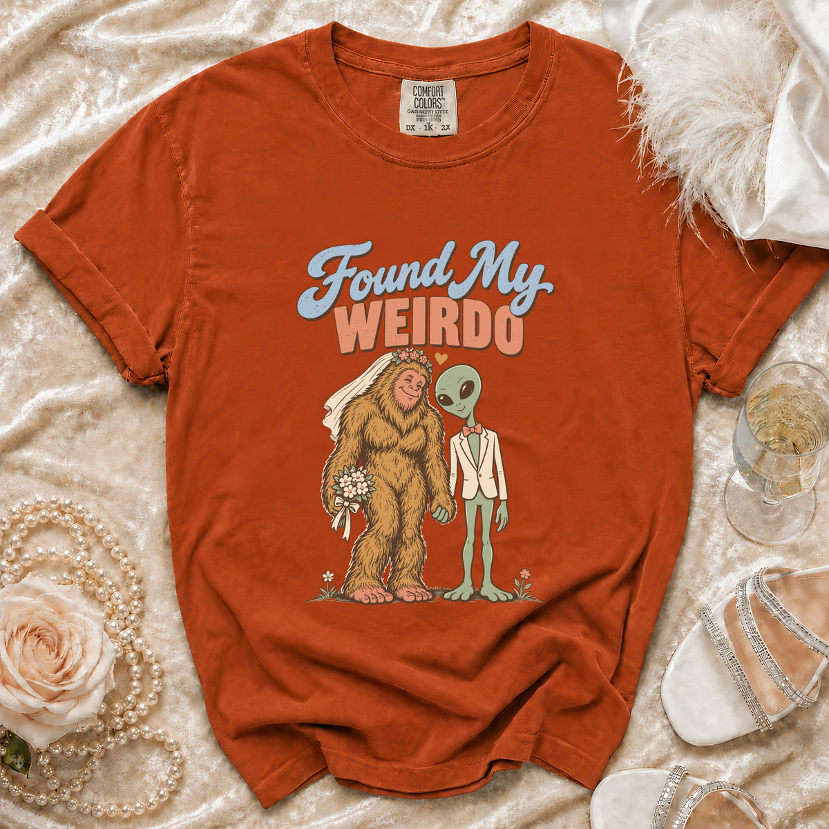 Orange t-shirt with Bigfoot bride and alien groom graphic saying "Found My Weirdo".