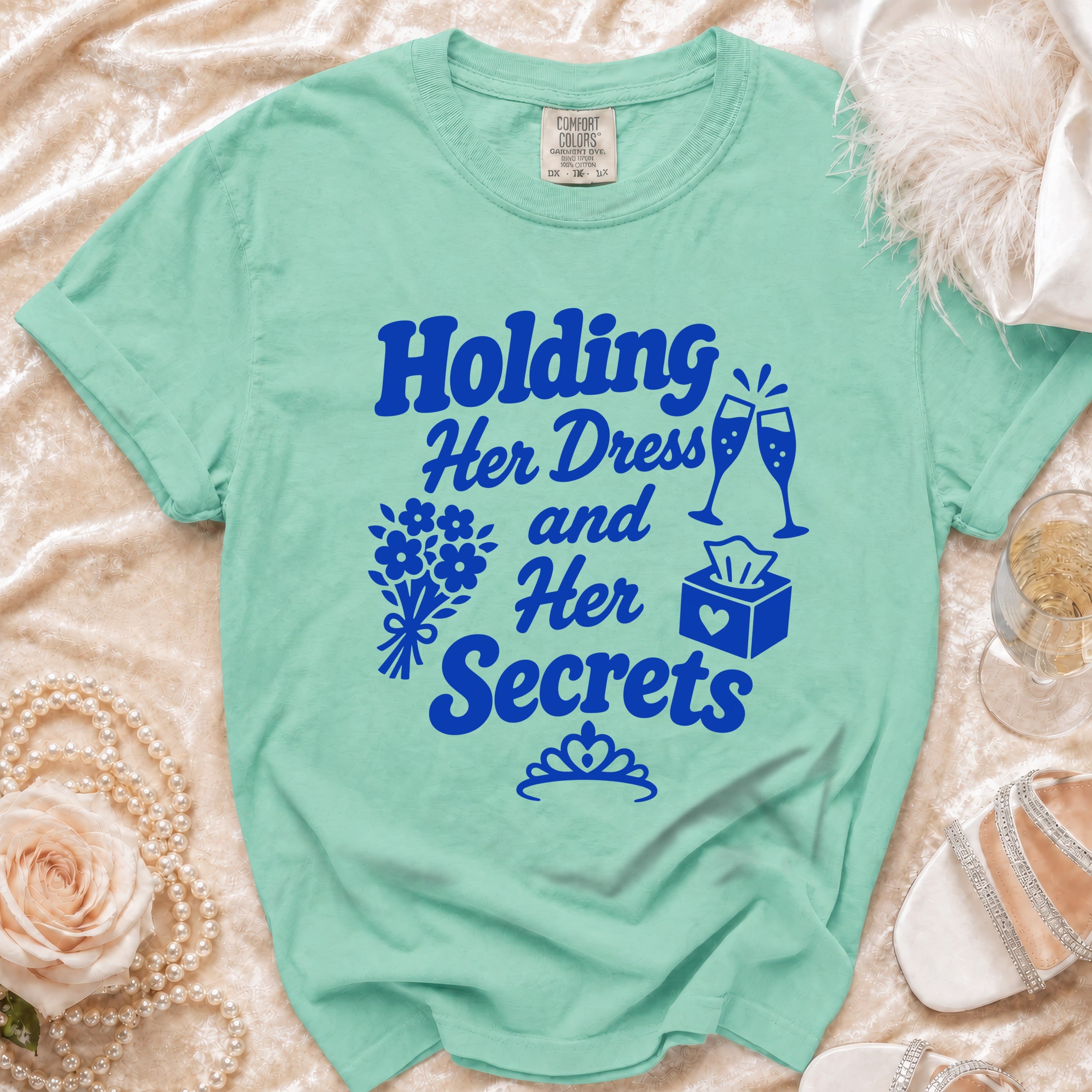 Mint green t-shirt with blue text "Holding Her Dress and Her Secrets".