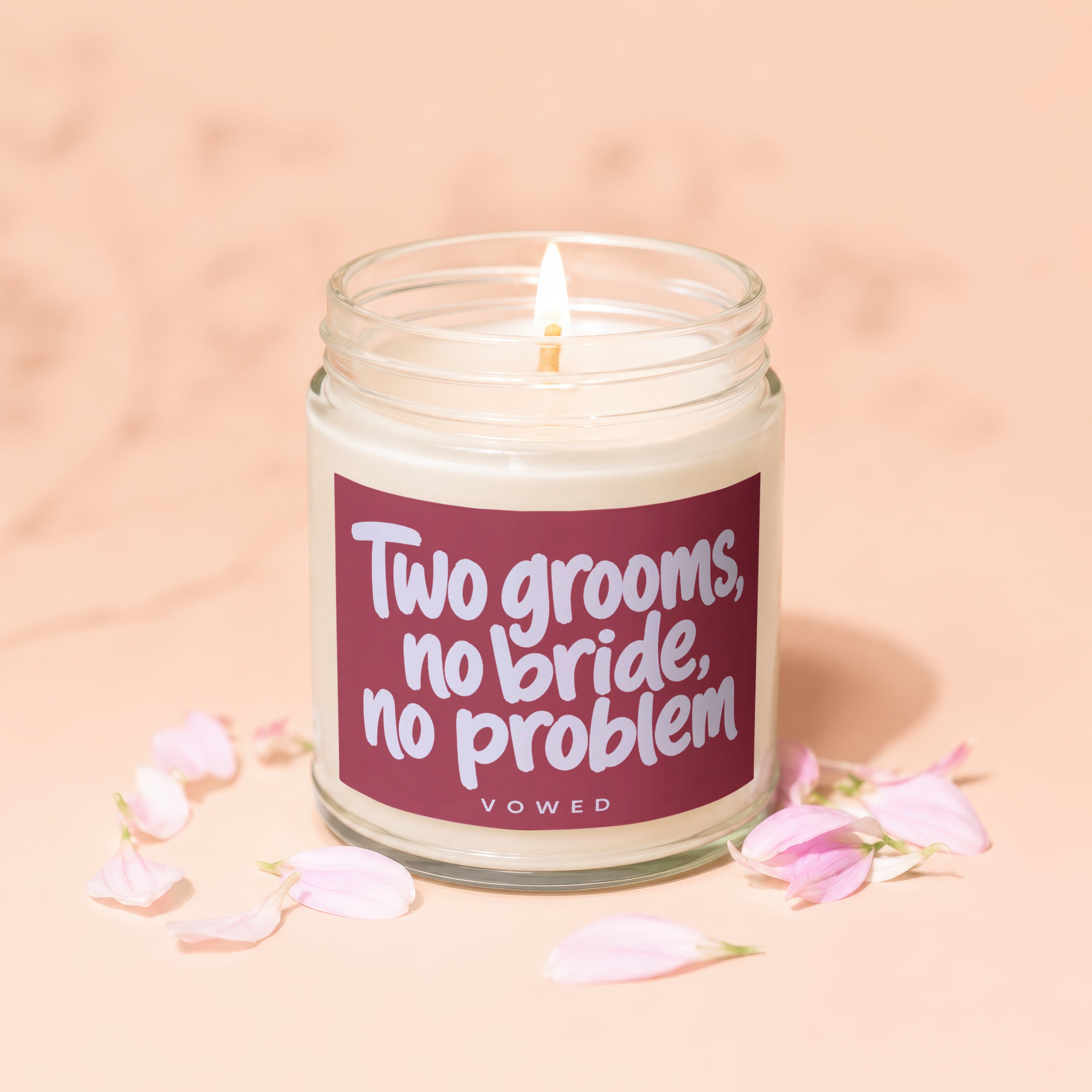 Candle with text "Two grooms, no bride, no problem" surrounded by petals.