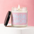 Burning candle in a glass jar with a pink label reading "We both said yes".