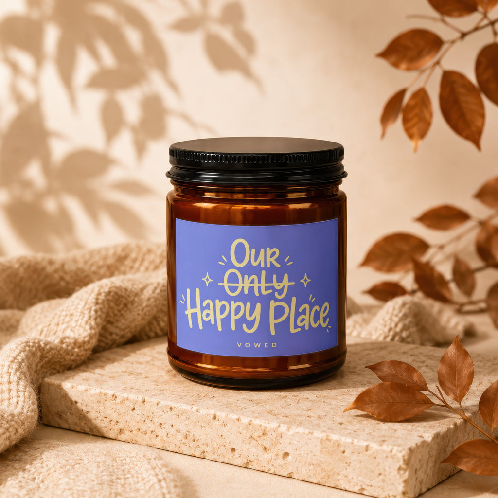 Amber candle with purple label reading "Our Only Happy Place Vowed".
