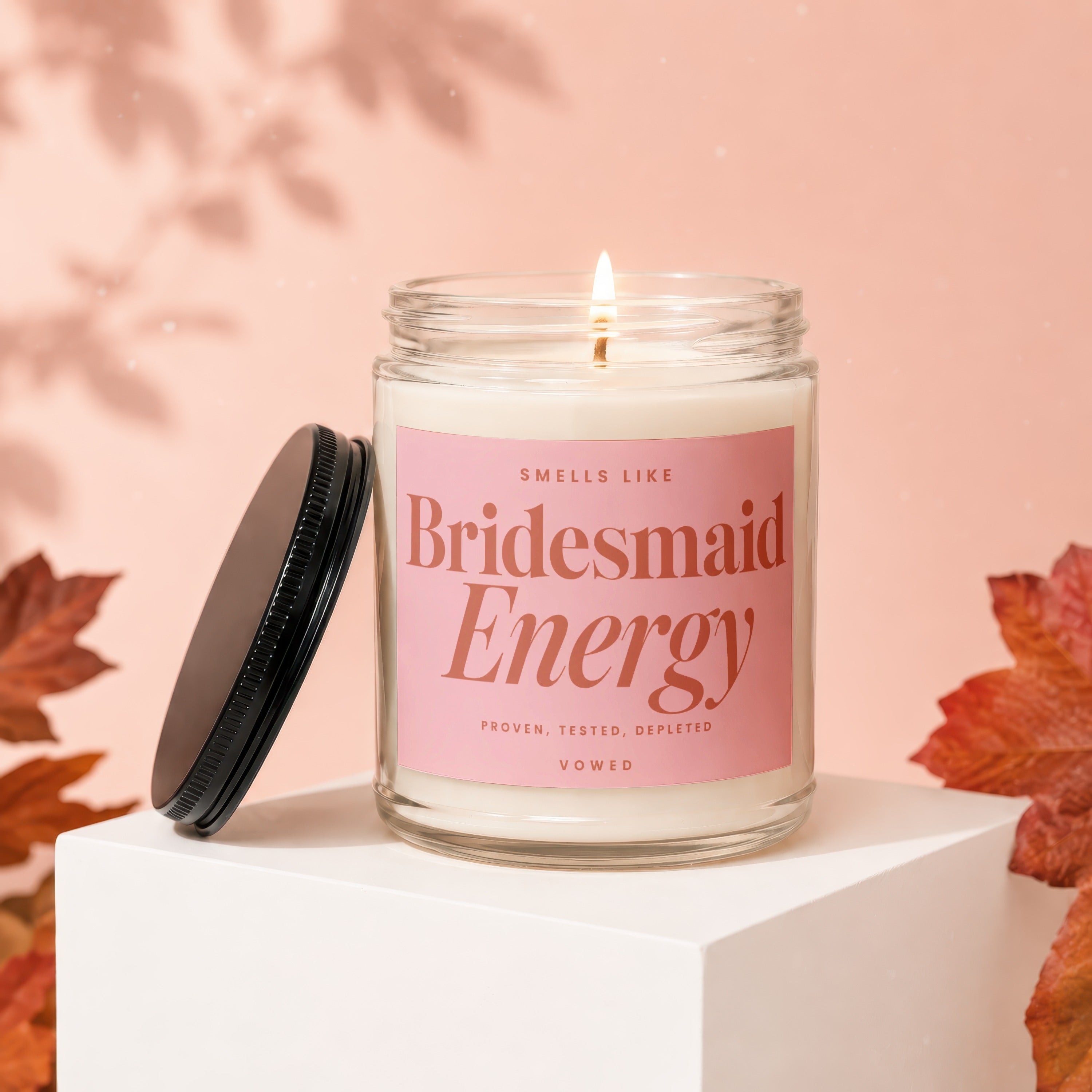 Lit candle in a glass jar with a pink label reading "Bridesmaid Energy".