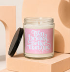 Candle with "Two brides, better than one" text on pink label, lid off.